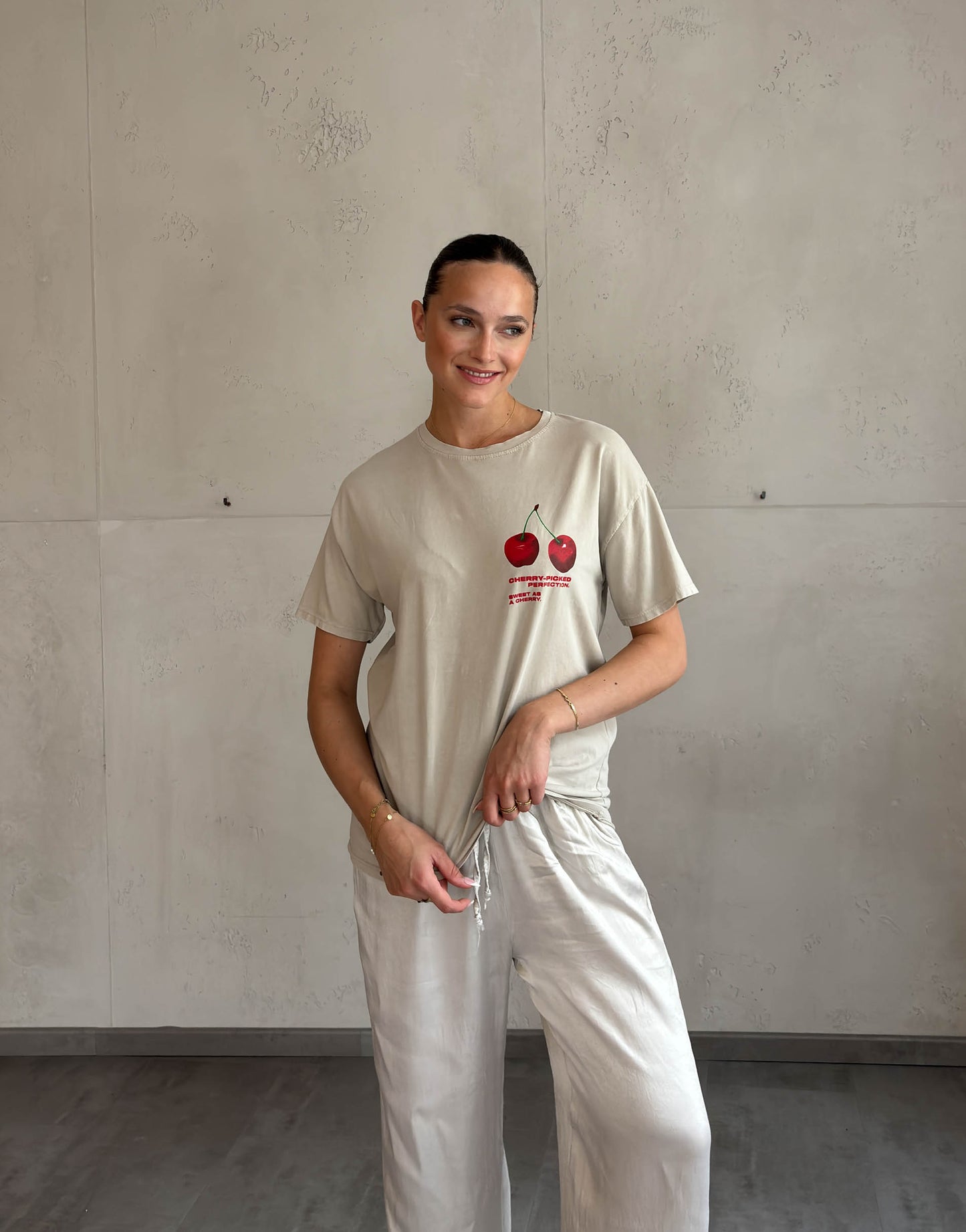 Frau mit brauen Haaren trägt beiges T-Shirt mit Cherry Print 