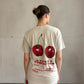 Frau mit brauen Haaren trägt beiges T-Shirt mit Cherry Print 