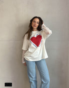 Frau mit braunen Haaren trägt weißes T-Shirt mit Print und Spitzeneinsatz am Arm