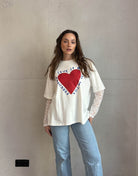 Frau mit braunen Haaren trägt weißes T-Shirt mit Print und Spitzeneinsatz am Arm