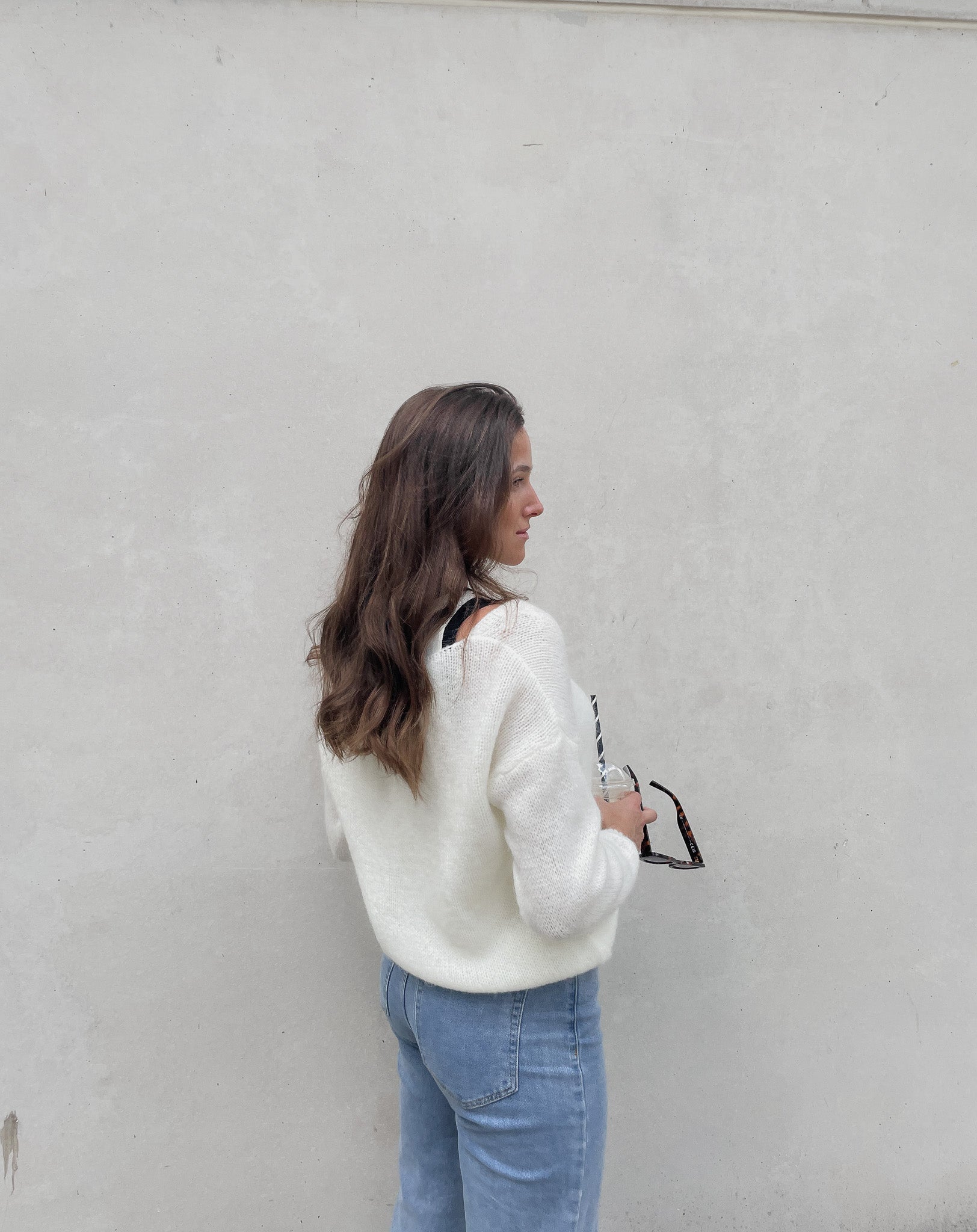 Frau mit brauen Haaren trägt kurze Mohair Strickjacke in Wollweiß