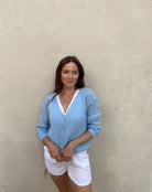 Frau mit brauen Haaren trägt kurze Mohair Strickjacke in hellblau