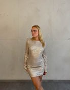 Frau mit blonden Haaren trägt kurzes Paillettenkleid in Gold