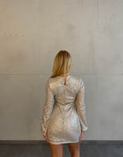 Frau mit blonden Haaren trägt kurzes Paillettenkleid in Gold