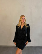 Frau mit blonden Haaren trägt mini Samtkleid in schwarz