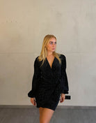 Frau mit blonden Haaren trägt mini Samtkleid in schwarz