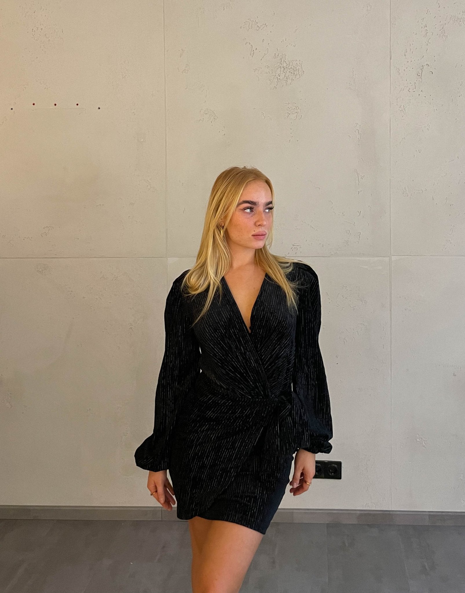 Frau mit blonden Haaren trägt mini Samtkleid in schwarz