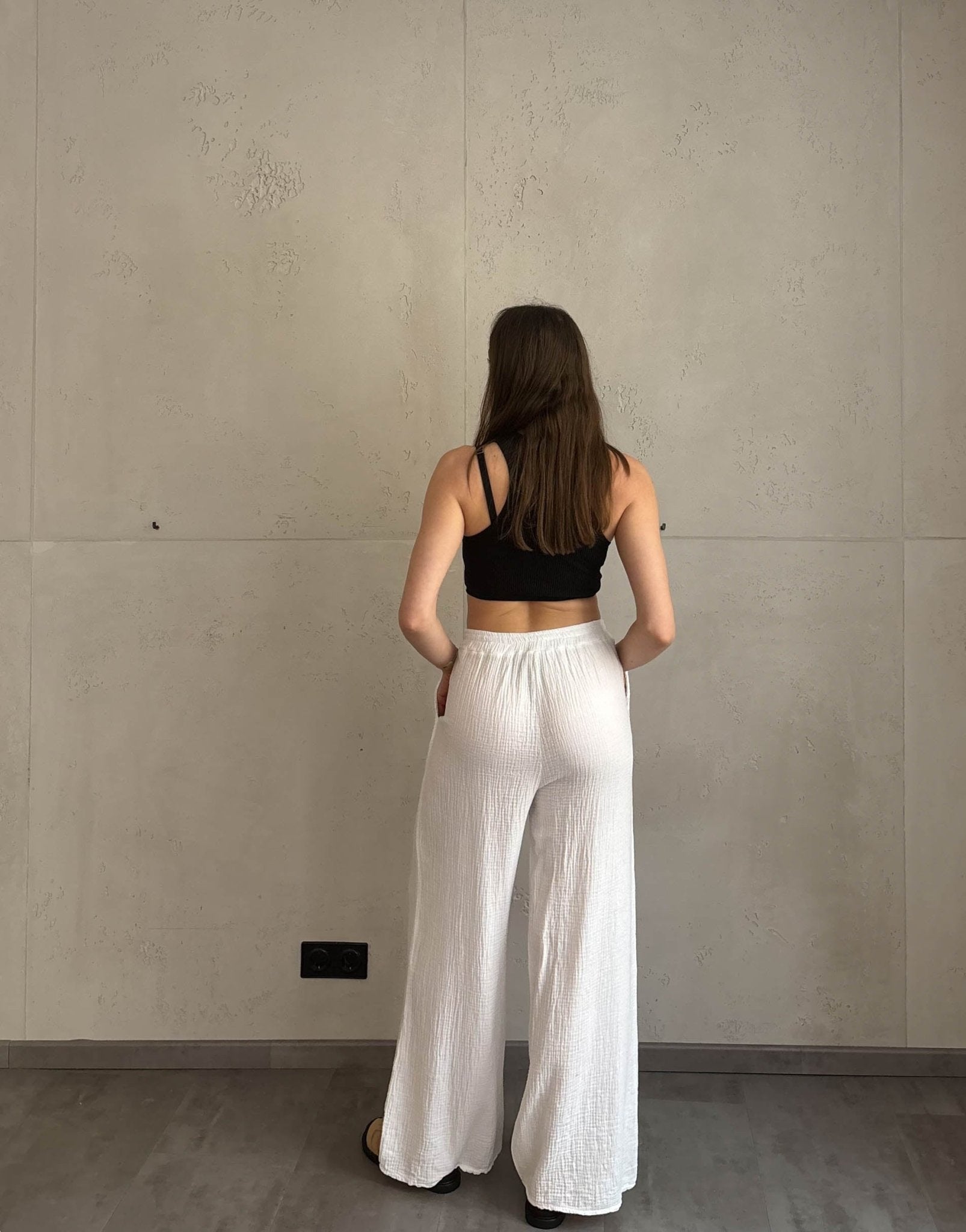 Frau mit brauen Haaren trägt klassische Musselinhose in weiß