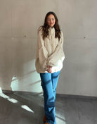 Frau mit brauen Haaren trägt oversize Strickjacke in Hellbeige