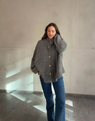 Frau mit brauen Haaren trägt oversize Strickjacke in Dunklegrau