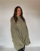 Frau mit brauen Haaren trägt oversize Pullover in oliv