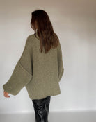 Frau mit brauen Haaren trägt oversize Pullover in oliv