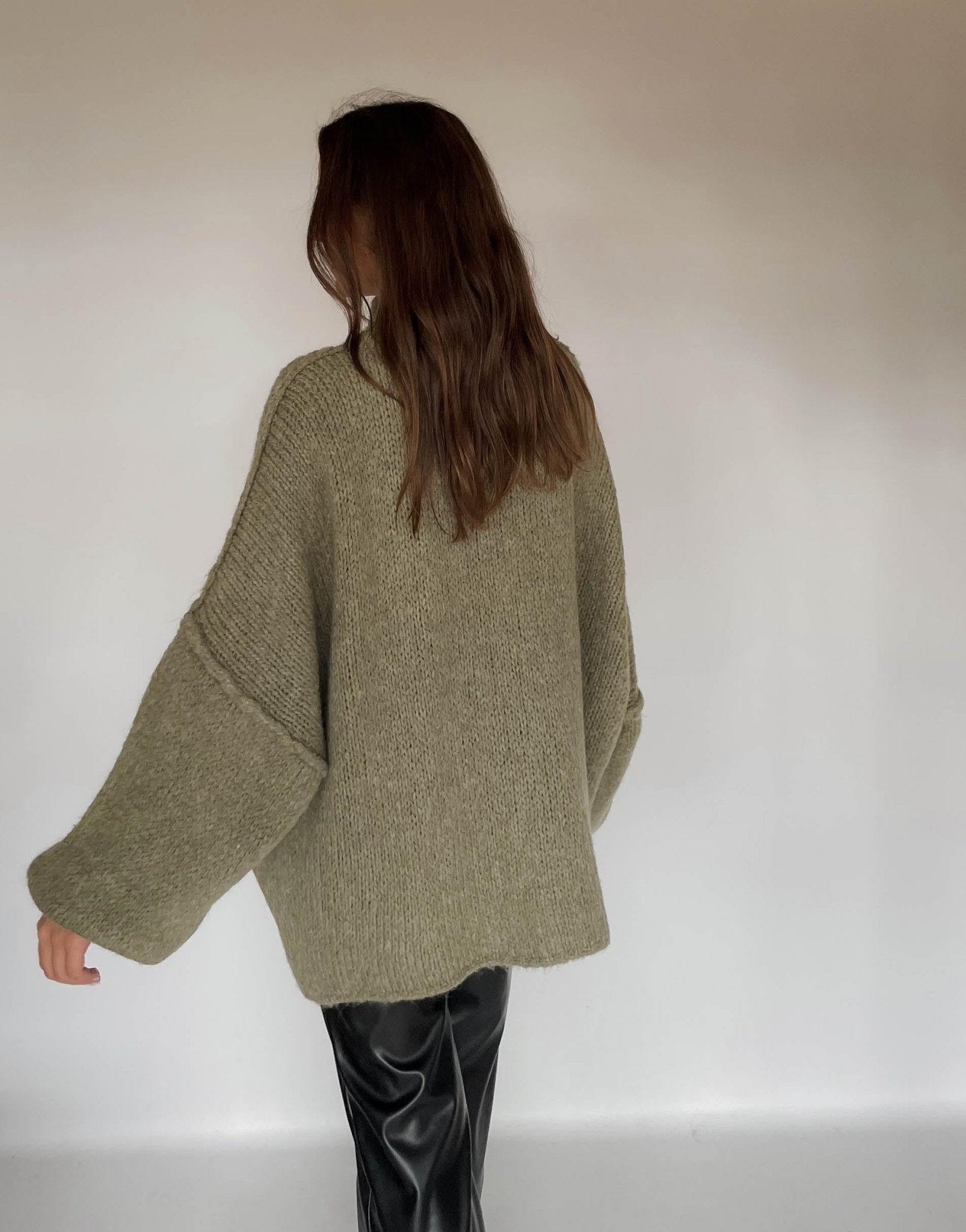 Frau mit brauen Haaren trägt oversize Pullover in oliv