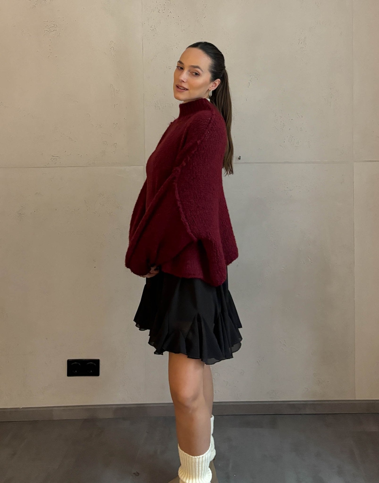 Frau mit braunen Haaren trägt kurzen oversize Pullover mit Stehkragen in Burgundy