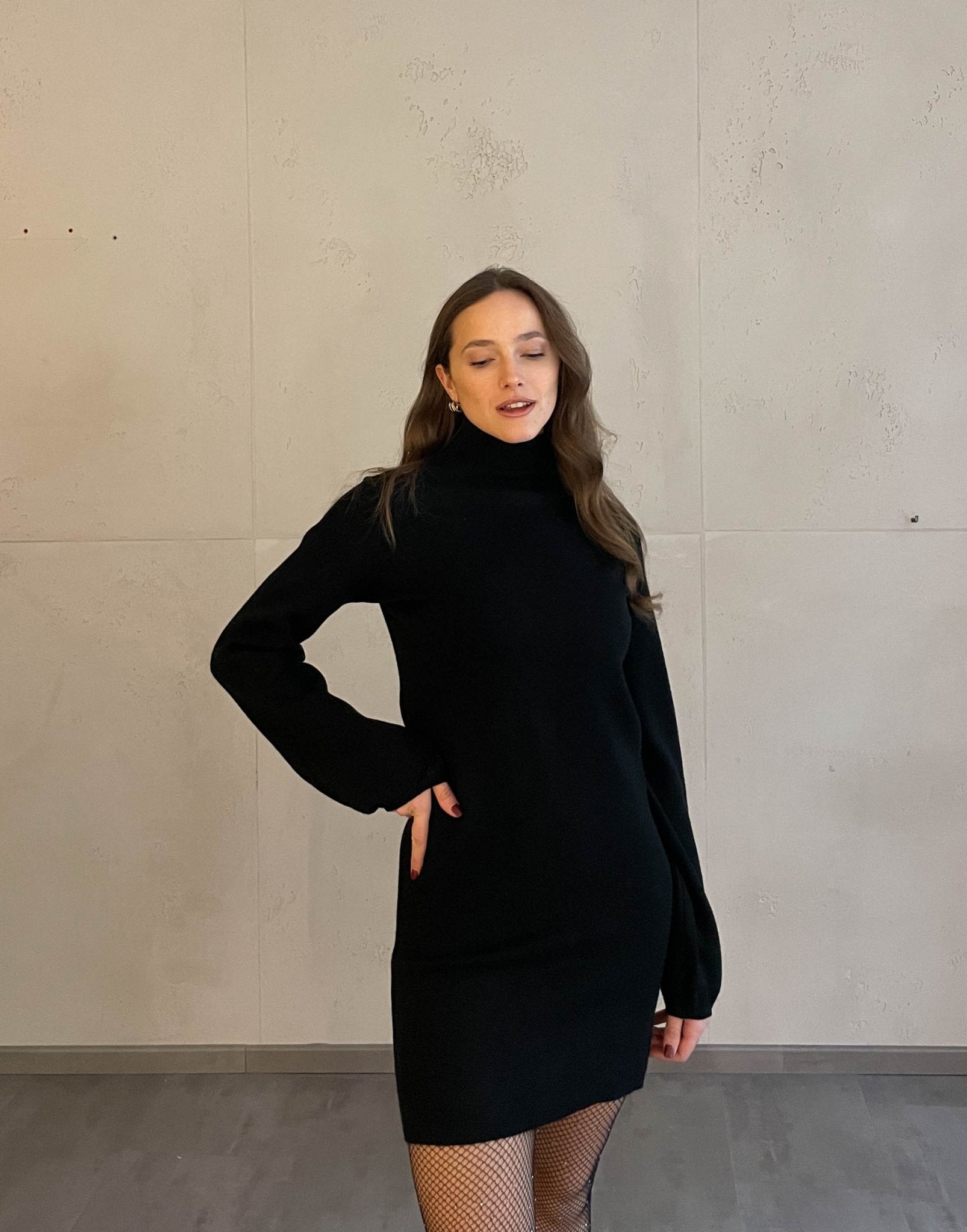 Frau mit brauen Haaren trägt schwarzes Strickkleid in schwarz 